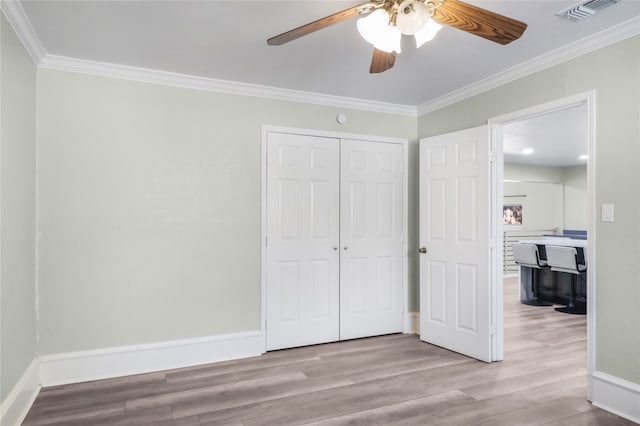 unfurnished bedroom featuring ceiling fan, light hardwood / wood-style floors, crown molding, and a closet