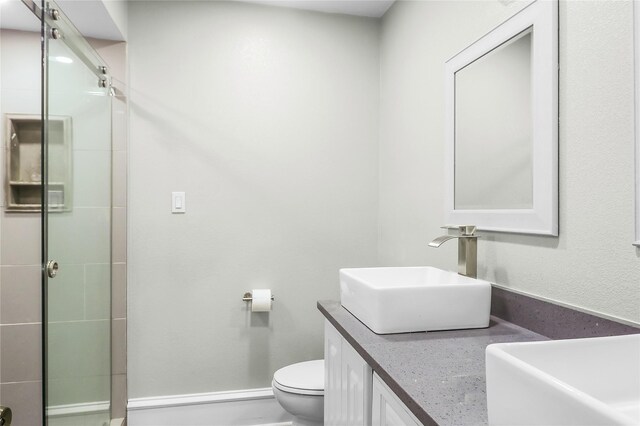 bathroom featuring a shower with door, vanity, and toilet