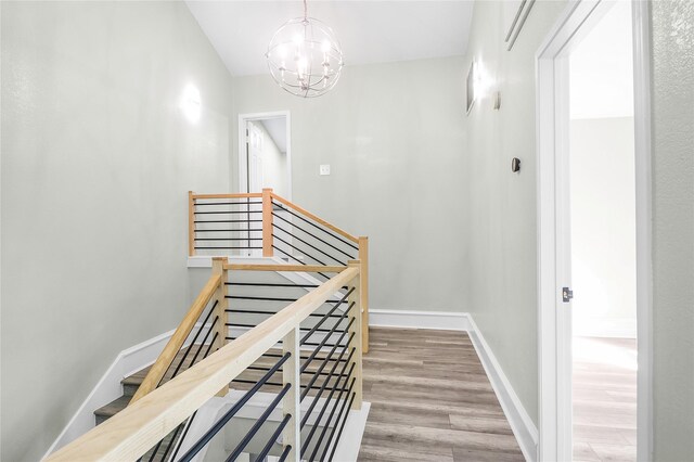 stairs with a notable chandelier and wood-type flooring