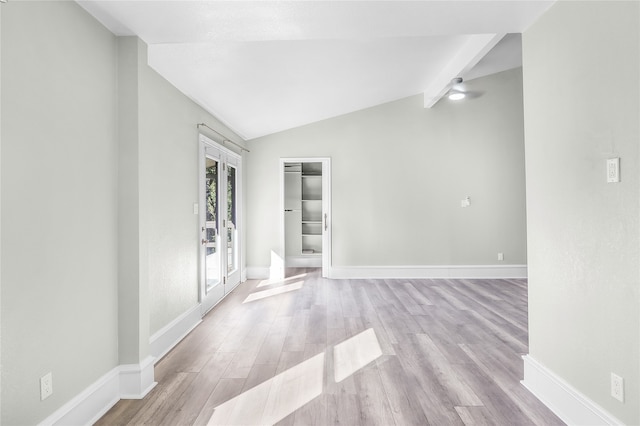 empty room with vaulted ceiling with beams and light hardwood / wood-style floors