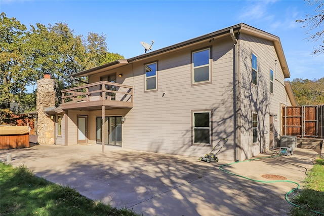 rear view of property with a patio area, a balcony, and a hot tub