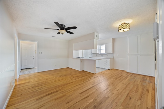 unfurnished living room with light hardwood / wood-style floors, sink, and a textured ceiling