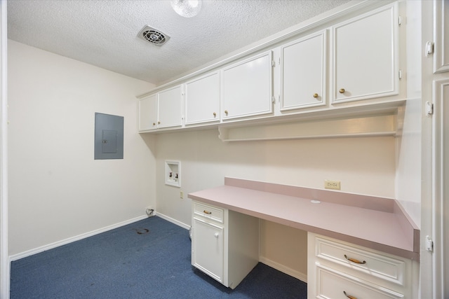 unfurnished office featuring carpet, a textured ceiling, built in desk, and electric panel