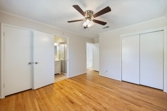 unfurnished bedroom featuring a textured ceiling, light wood-type flooring, ensuite bath, and ceiling fan