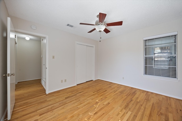 unfurnished bedroom featuring ceiling fan, light wood-type flooring, and a textured ceiling