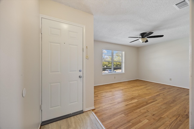 entryway featuring ceiling fan, light hardwood / wood-style floors, and a textured ceiling