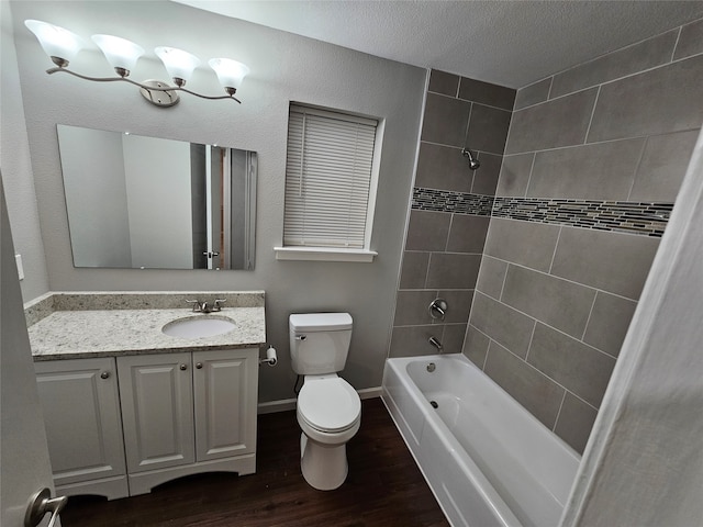 full bathroom featuring tiled shower / bath combo, wood-type flooring, a textured ceiling, toilet, and vanity