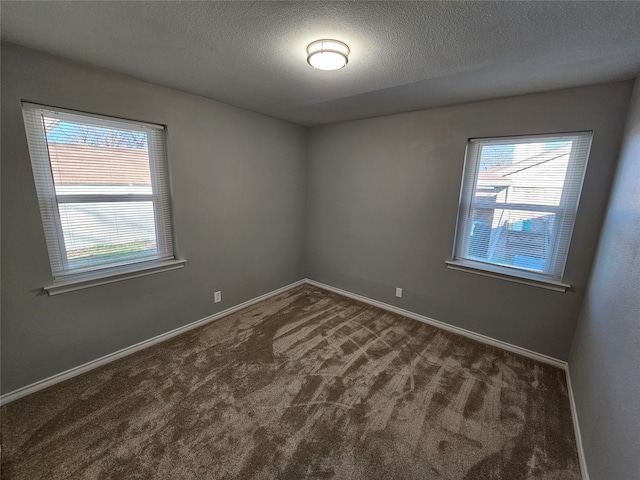 empty room featuring dark colored carpet and a textured ceiling