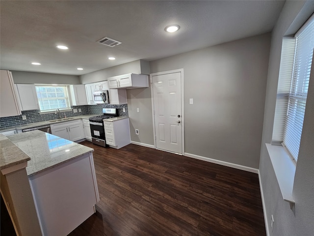 kitchen featuring kitchen peninsula, stainless steel appliances, dark wood-type flooring, sink, and white cabinetry