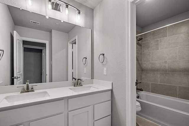 full bathroom featuring toilet, vanity, and tiled shower / bath