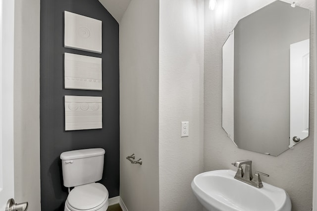 bathroom with sink, lofted ceiling, and toilet