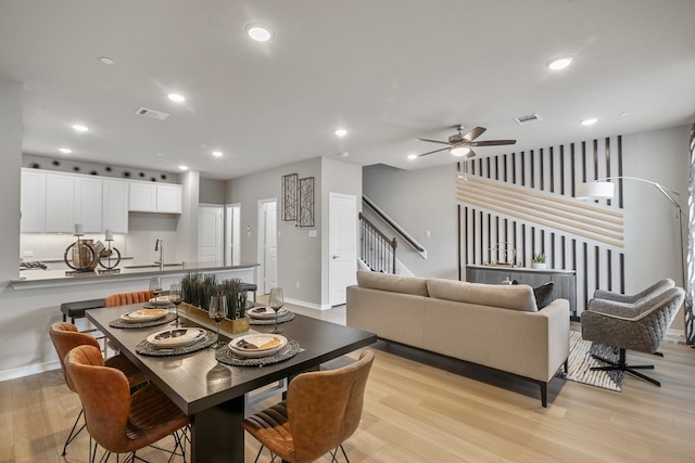 dining space with light hardwood / wood-style flooring, ceiling fan, and sink