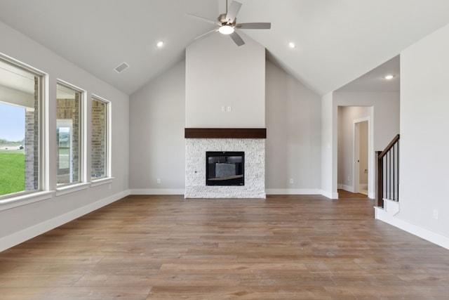 unfurnished living room with high vaulted ceiling, light hardwood / wood-style floors, and a stone fireplace