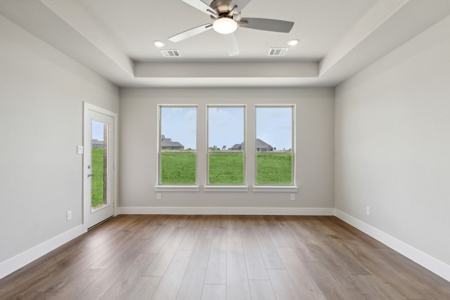 unfurnished room featuring hardwood / wood-style flooring, ceiling fan, and a tray ceiling