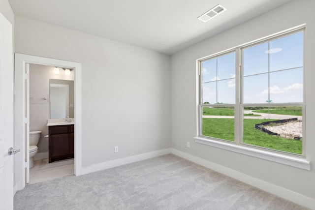 unfurnished bedroom featuring sink, light carpet, and connected bathroom