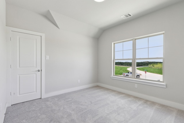 spare room featuring light colored carpet and vaulted ceiling