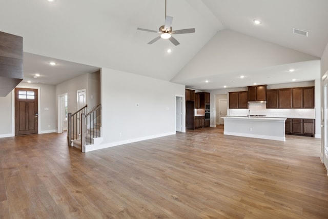 unfurnished living room featuring ceiling fan, light wood-type flooring, and high vaulted ceiling