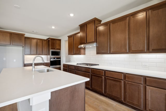 kitchen featuring a center island with sink, sink, and stainless steel appliances