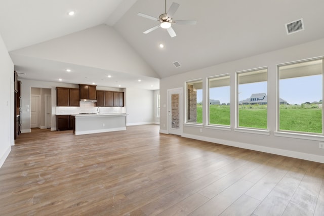 unfurnished living room featuring ceiling fan, sink, beam ceiling, high vaulted ceiling, and light hardwood / wood-style floors