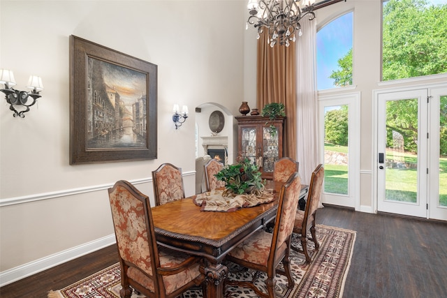 dining space with a towering ceiling, a chandelier, and dark hardwood / wood-style flooring