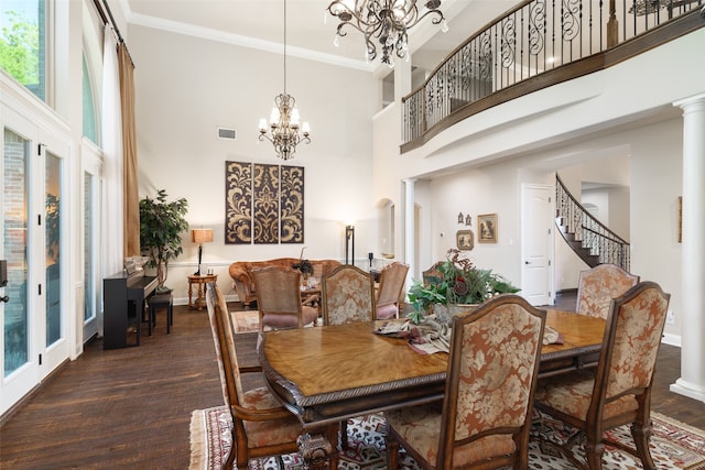 dining area with crown molding, dark wood-type flooring, a high ceiling, a notable chandelier, and ornate columns