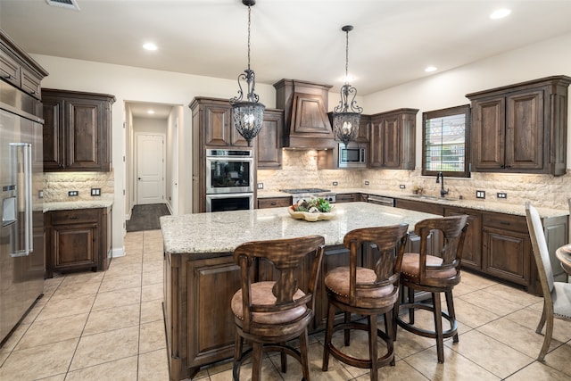 kitchen with sink, custom exhaust hood, built in appliances, a kitchen island, and pendant lighting