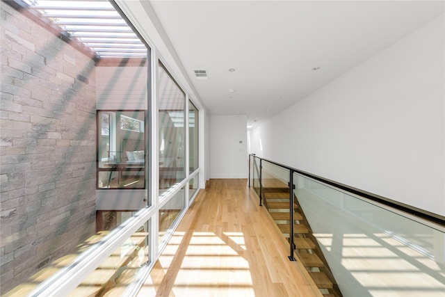 corridor with brick wall and light hardwood / wood-style flooring