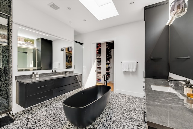 bathroom with vanity, a skylight, and a bathing tub