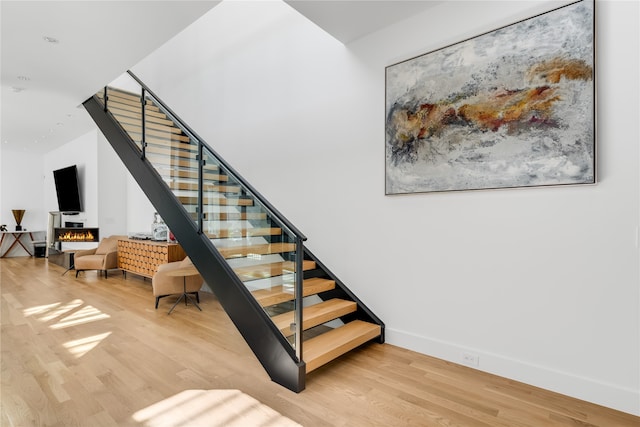 stairway featuring a fireplace and hardwood / wood-style floors