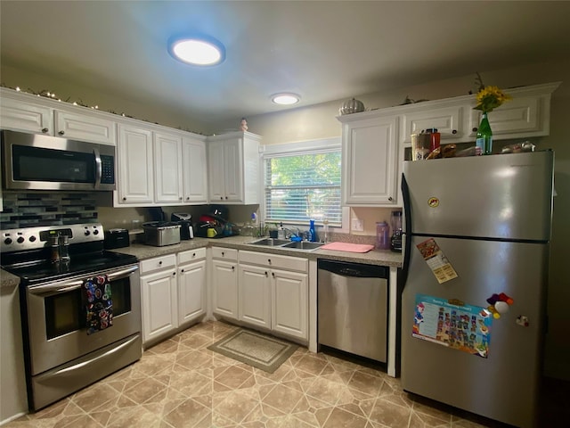 kitchen featuring decorative backsplash, appliances with stainless steel finishes, sink, white cabinetry, and light tile patterned flooring