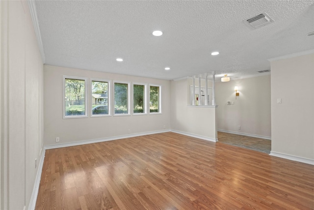 spare room featuring crown molding, a textured ceiling, and light hardwood / wood-style flooring