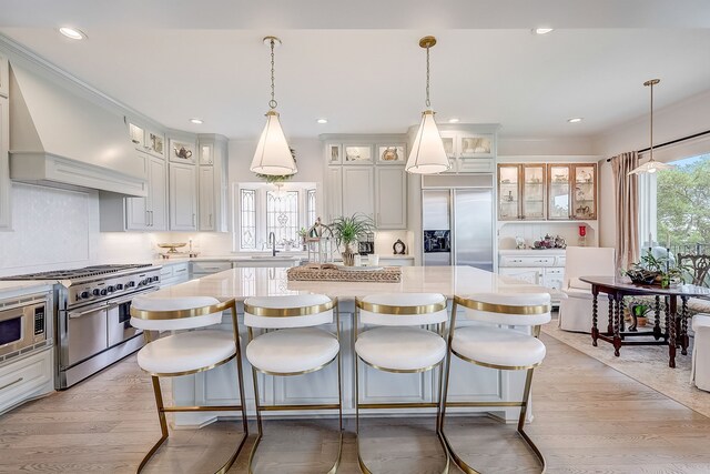 kitchen featuring white cabinets, a center island, built in appliances, and light hardwood / wood-style floors