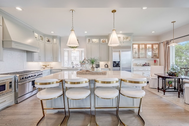 kitchen featuring white cabinets, a center island, built in appliances, and light hardwood / wood-style floors