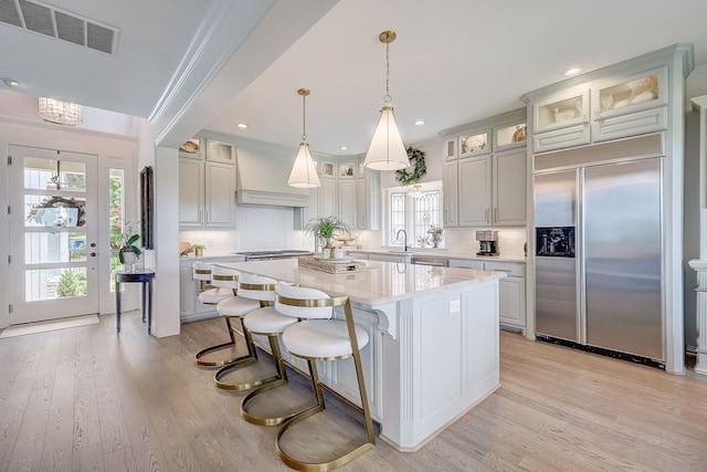 kitchen featuring decorative backsplash, a center island, light hardwood / wood-style floors, and built in fridge