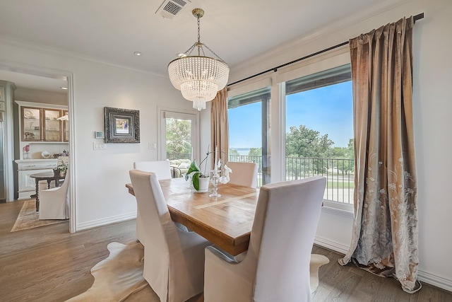 dining room with hardwood / wood-style flooring, an inviting chandelier, and crown molding