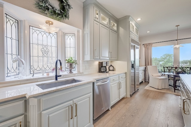 kitchen with white cabinetry, stainless steel appliances, light wood-type flooring, and a notable chandelier