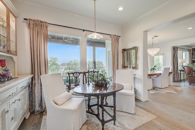 dining area featuring crown molding, light hardwood / wood-style floors, and an inviting chandelier