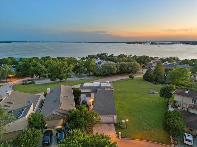 aerial view at dusk featuring a water view