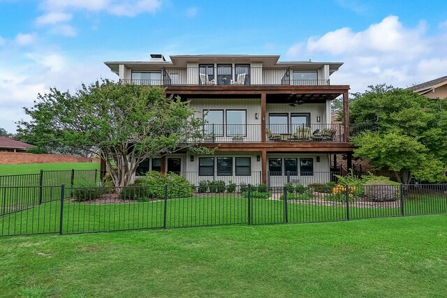 rear view of property featuring a lawn and a balcony