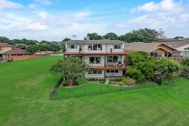 rear view of property featuring a balcony and a yard