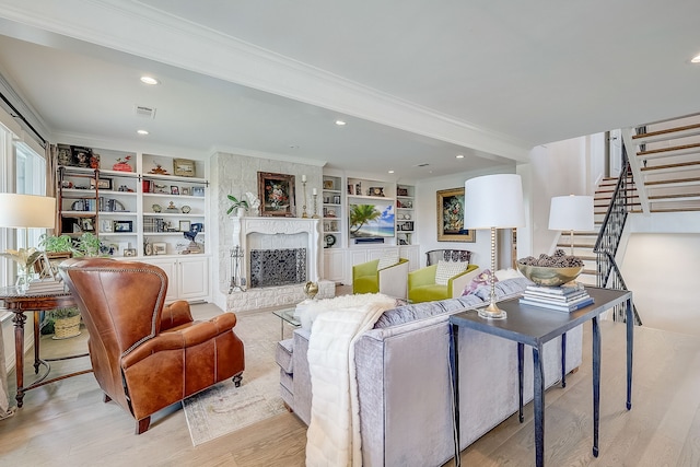 living room with a fireplace, light hardwood / wood-style flooring, built in features, and crown molding