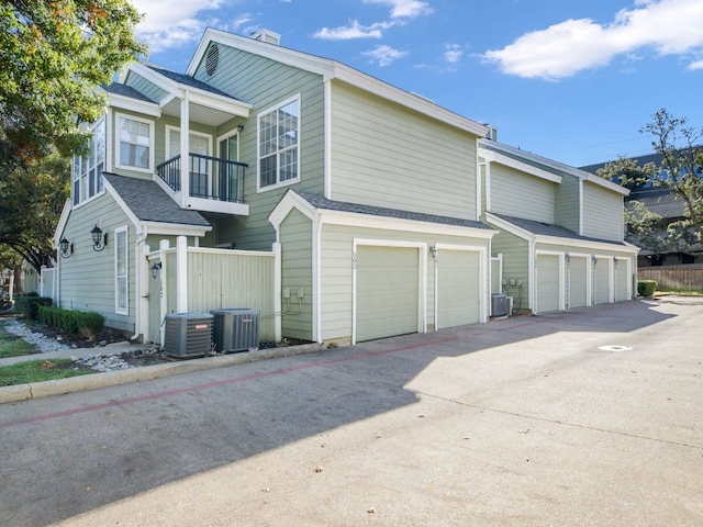 view of property exterior featuring central AC, a balcony, and a garage