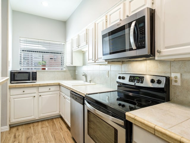 kitchen featuring white cabinetry, sink, appliances with stainless steel finishes, and light hardwood / wood-style flooring