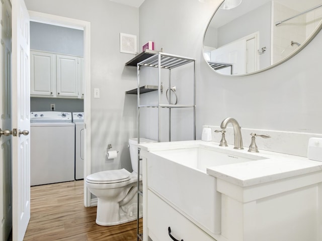 bathroom with washing machine and dryer, vanity, wood-type flooring, and toilet