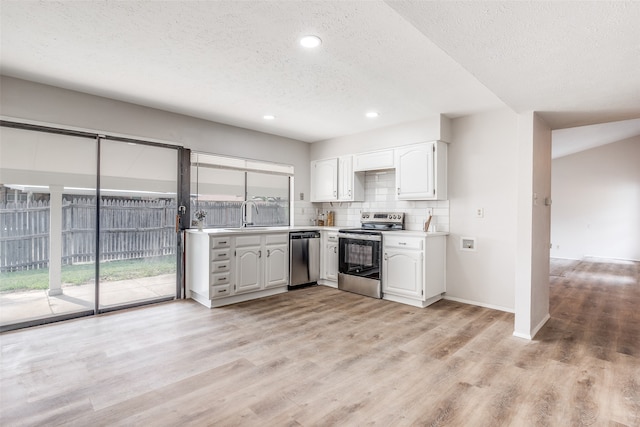 kitchen featuring decorative backsplash, white cabinets, light wood-type flooring, and appliances with stainless steel finishes