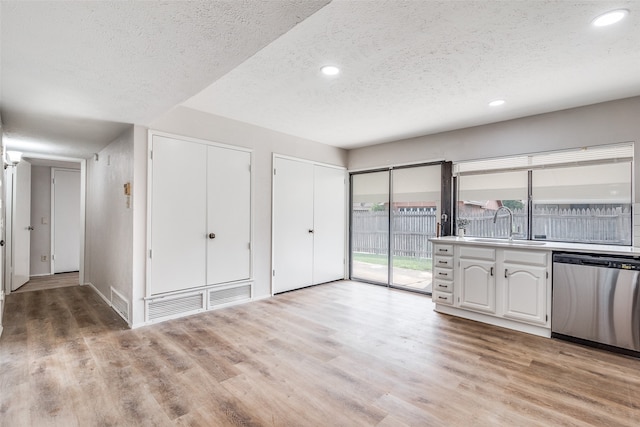 kitchen featuring dishwasher, sink, light hardwood / wood-style flooring, a textured ceiling, and white cabinetry