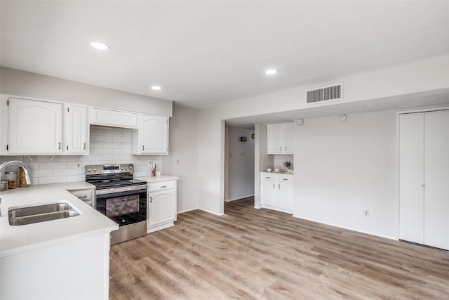 kitchen featuring sink, tasteful backsplash, electric stove, white cabinets, and light wood-type flooring