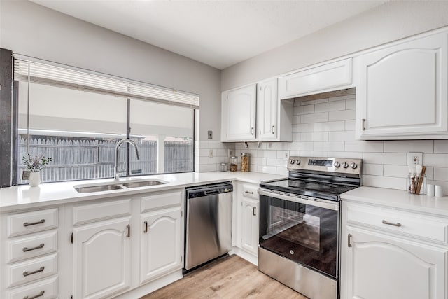 kitchen featuring white cabinetry, sink, stainless steel appliances, and light wood-type flooring