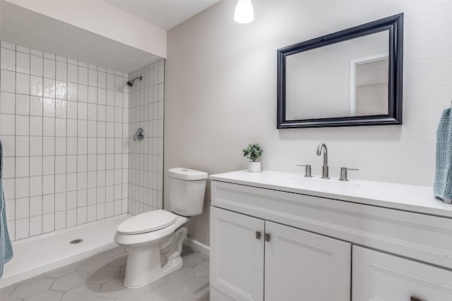 bathroom featuring tiled shower, tile patterned floors, vanity, and toilet