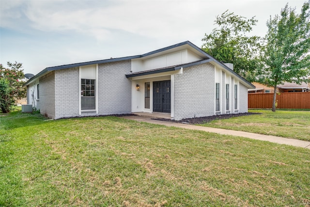 view of front of home with central air condition unit and a front yard